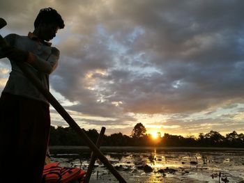 Man standing by sea against sky during sunset