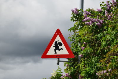 Warning sign on road against sky