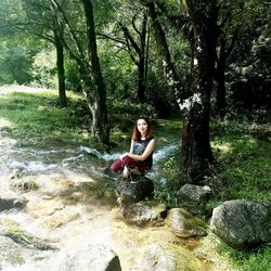 Portrait of young woman sitting on tree trunk