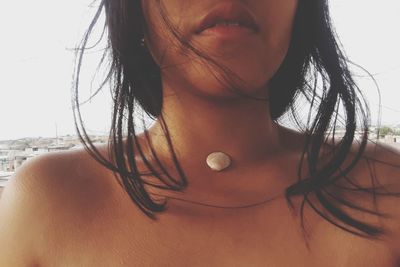 Midsection of woman with seashell on neck at beach