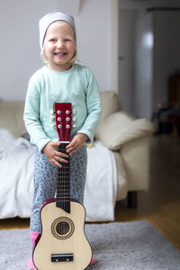 Portrait of happy boy holding guitar at home