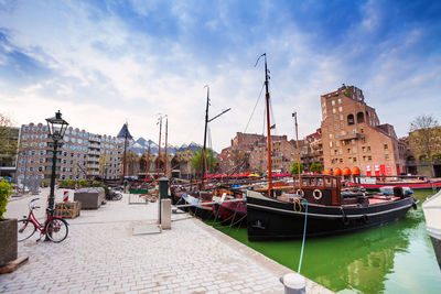 Boats moored at harbor in city against sky