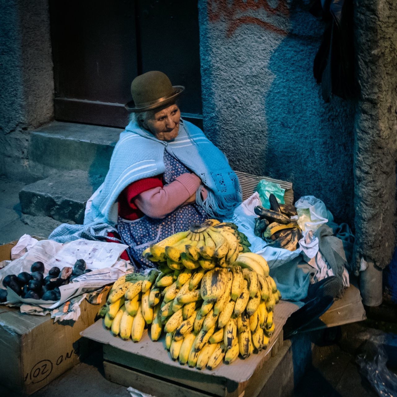 one person, food and drink, food, healthy eating, real people, market, sitting, market stall, fruit, hat, choice, wellbeing, freshness, selling, retail, banana, clothing, variation, for sale, retail display