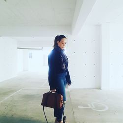 Full length of woman standing against wall in building