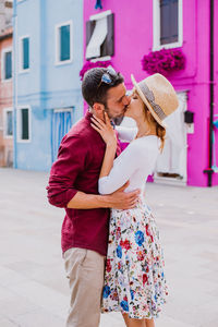 Couple embracing while standing against building outdoors