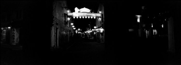 Illuminated street amidst buildings in city at night