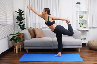 Yung adult healthy lifestyle practicing yoga in living room, dancers / natarajasanayoga pose