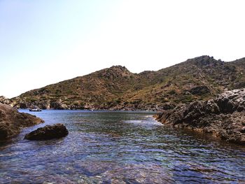 Scenic view of sea and mountains against clear sky