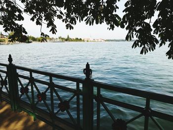 Silhouette woman sitting on railing by sea against clear sky