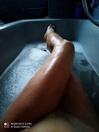 Low section of woman relaxing in bathroom