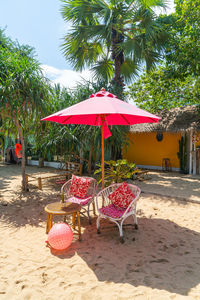 Red flags on chair at beach against trees