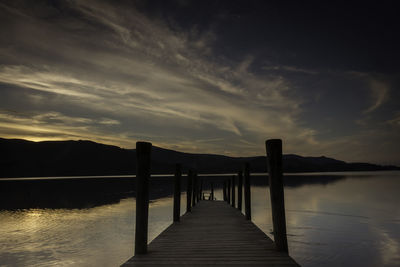 Pier over lake against sky during sunset