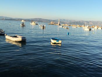 Boats moored in lake against clear sky