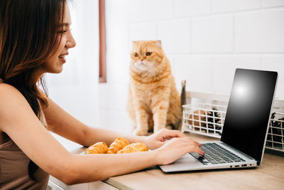 Side view of woman using laptop at home