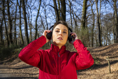 Beautiful woman with short hair is listening to the music while she walks in the park.
