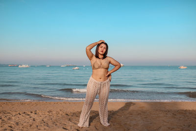 Full length of woman standing at beach against clear sky