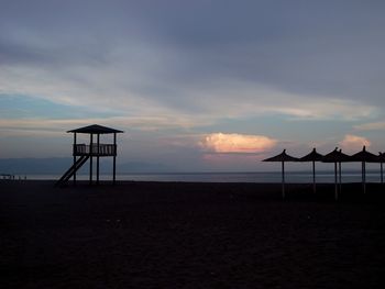 Lifeguard hut on beach against sky during sunset