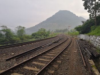 Railroad tracks by mountain against sky