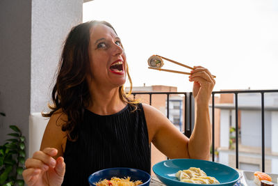 Portrait of young woman having food at home