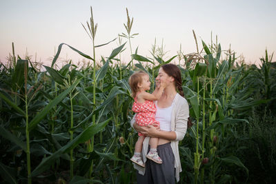 Mother and daughter on field against plants