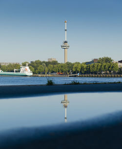Tower by river against clear blue sky