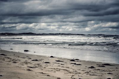 Scenic view of beach against cloudy sky