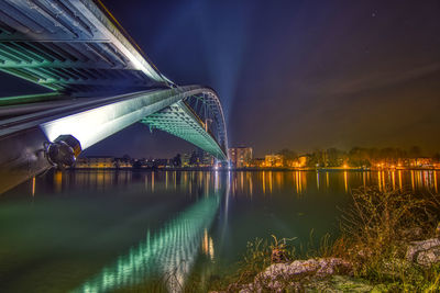 Illuminated bridge over river at night