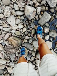 Low section of woman standing on pebbles