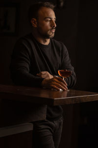 Side view of man holding coffee at home