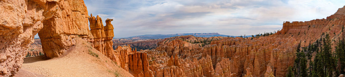 Panoramic view of rocky mountains against cloudy sky