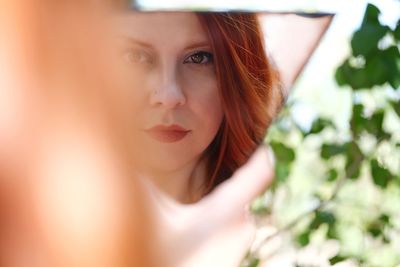 Close-up portrait of beautiful woman standing by plant outdoors