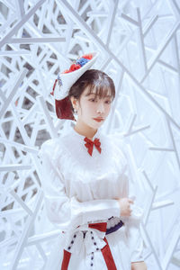 Portrait of young woman standing against wall