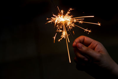 Hand holding firework display at night
