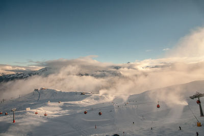 Scenic view of ski lift over snowcapped mountain against sky