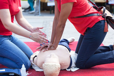 Instructor explaining rescue worker while giving cpr to mannequin