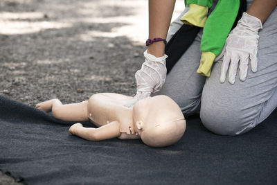 Midsection of paramedics performing cpr on baby mannequin