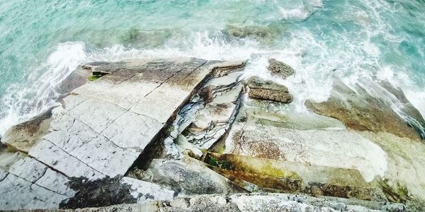 High angle view of sea waves splashing on rocks