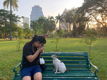 Full length of young woman sitting on grass against trees