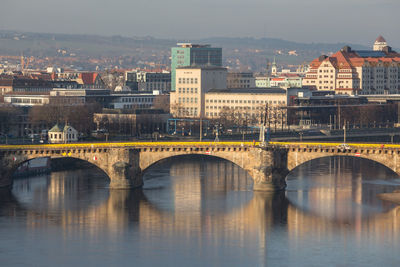 Arch bridge over river in city against sky