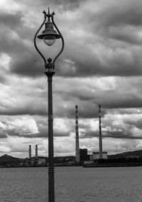 Street light in city against cloudy sky