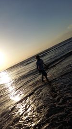 Man on beach against sky during sunset