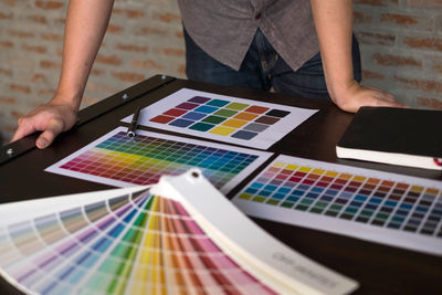 Midsection of design professional with color swatches on table