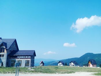 Houses on field against blue sky