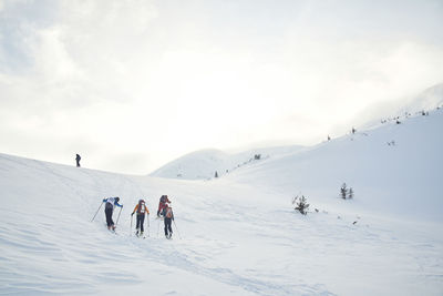 People skiing on snowcapped mountain against sky