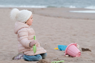 Little girl is digging in the sand on a cold day at the beach