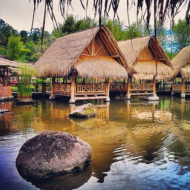 architecture, water, built structure, building exterior, reflection, tree, waterfront, river, sky, lake, house, rippled, outdoors, day, no people, rock - object, nature, sunlight, tranquility, pond