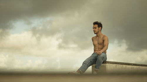 Shirtless man standing against sky