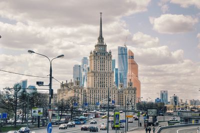 Traffic on city street against cloudy sky