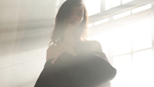 Portrait of woman standing against window