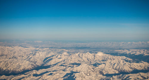 Scenic view of snowcapped mountains against blue sky